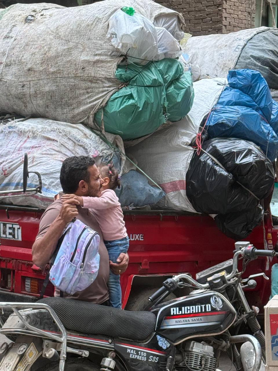 Desa sampah di Kairo, gang sempit, pikap merah, gunungan karung pilahan.