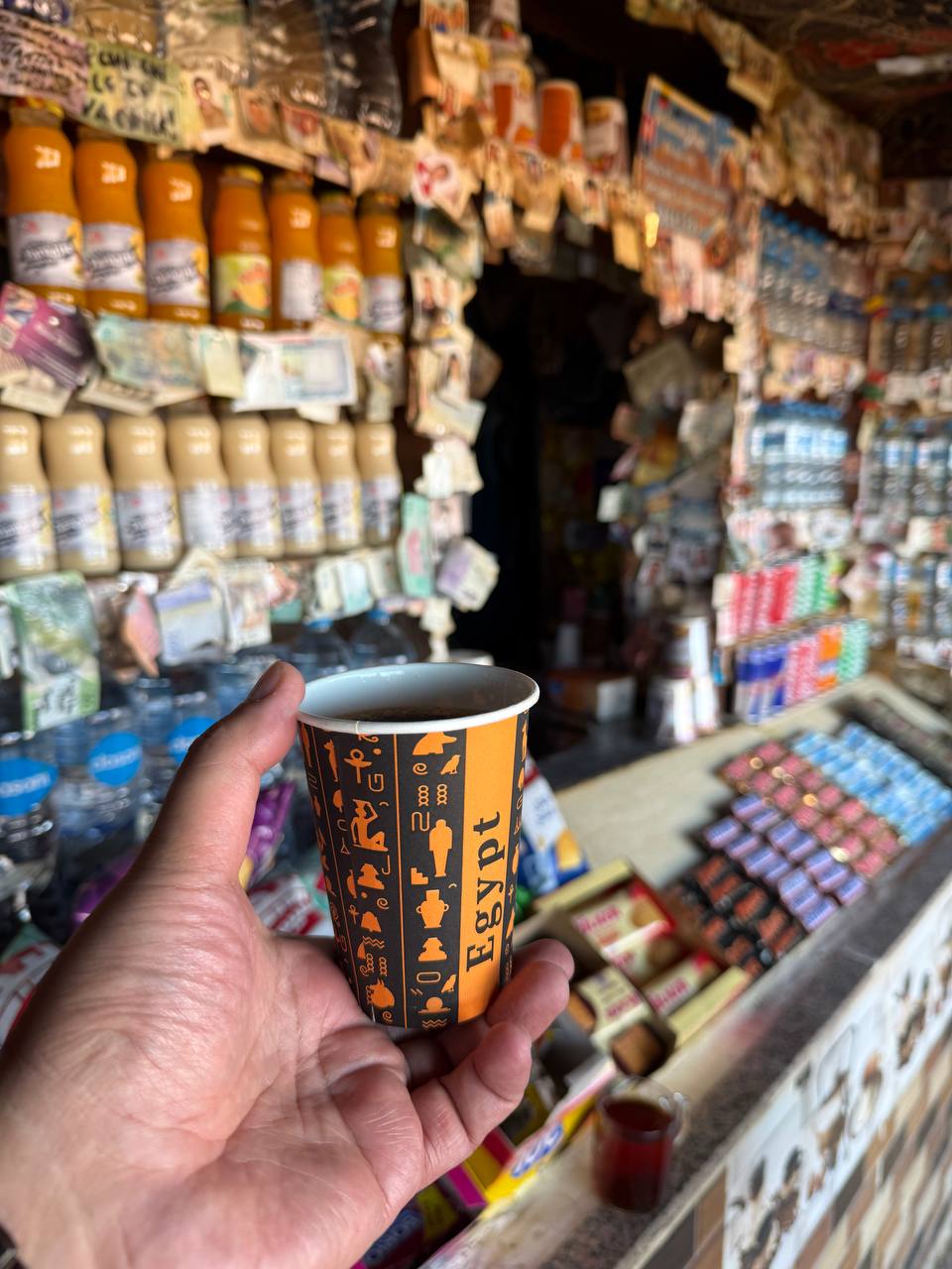 Penjual berkain kepala kotak-kotak ikut tersenyum di belakang konter.