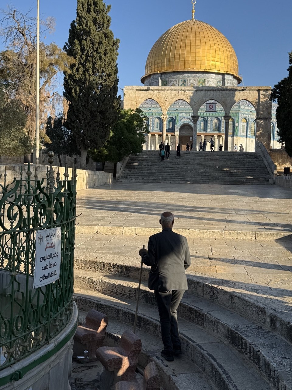 Deretan lengkung bata Temple Mount, merpati bertengger di balok atas, kota luas di bawah langit pekat.