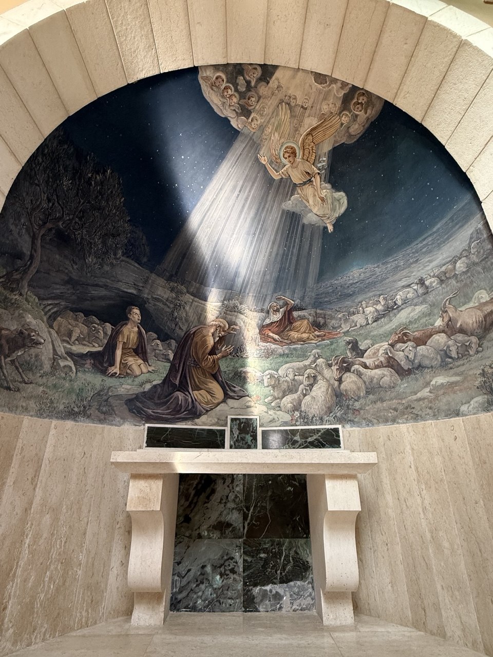 Mural pengumuman malaikat di atas altar, tiga gembala, tiga wajah; dan seekor anjing penjaga yang meringkuk di tepi padang.