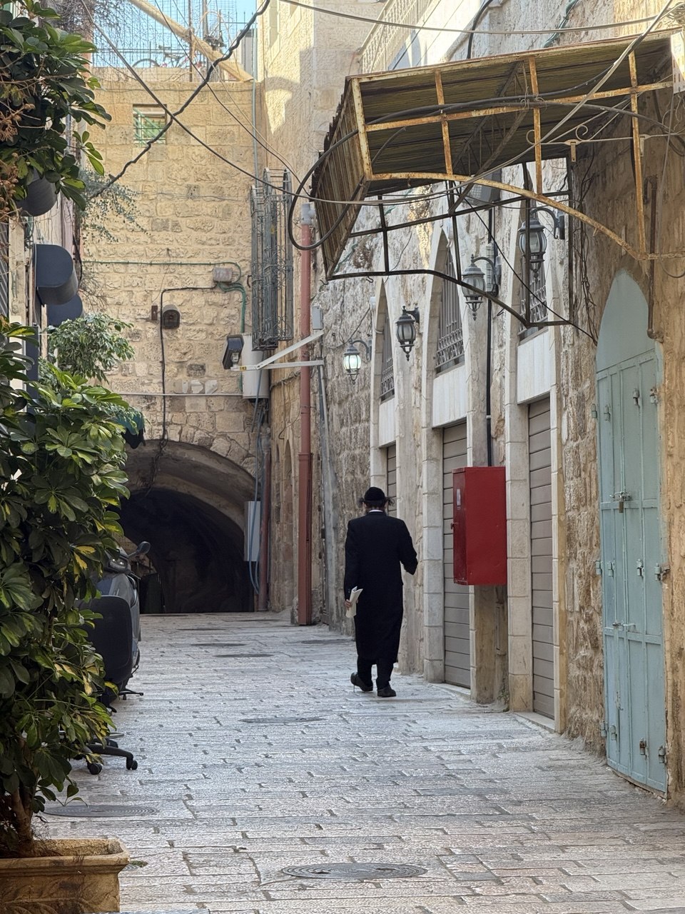 Lorong Kota Tua di rute Via Dolorosa, pria Hasidik berjubah hitam berjalan seperti keluar dari sebuah lukisan.