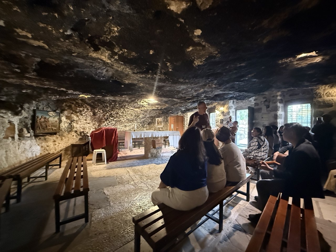 Rombongan mengikuti ibadah di gereja Padang Gembala, Beit Sahour, bangku kayu dan altar sederhana di bawah langit-langit batu.