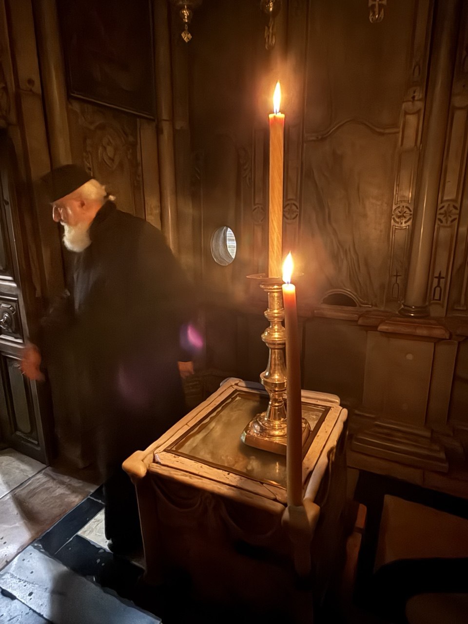 Imam Ortodoks dan lilin tinggi di dalam Makam Kudus, mendaftarkan doa entah untuk siapa.